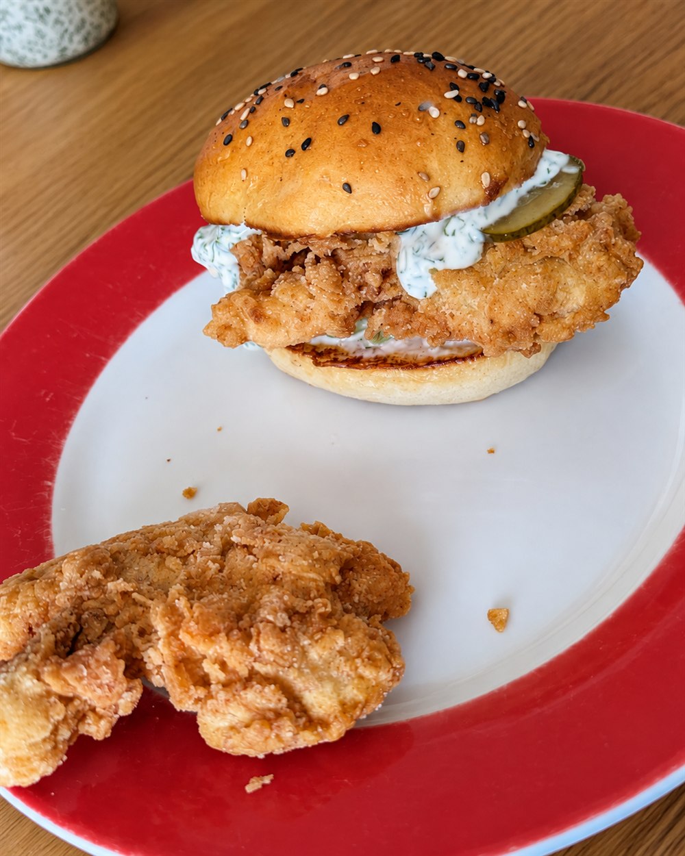 Nahaufnahme eines Chicken-Burgers aus meinen Kochversuchen: Bun, panierte Füllung, Sauce und Gurke.